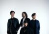 REVNOIR : un premier album en vue Portrait de groupe des quatre membres de Revnoir en tenues sombres sur fond blanc