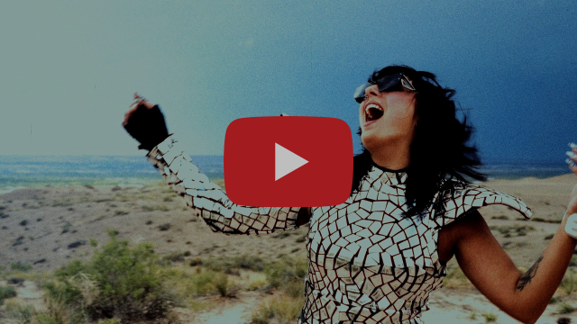 Chanteuse en tenue argentée lançant les bras en l'air dans un paysage désertique, image extraite du clip de « Starshine »