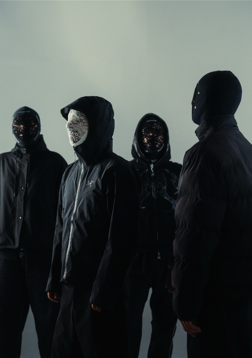 Quatre silhouettes masquées et vêtues de noir, debout sur fond gris