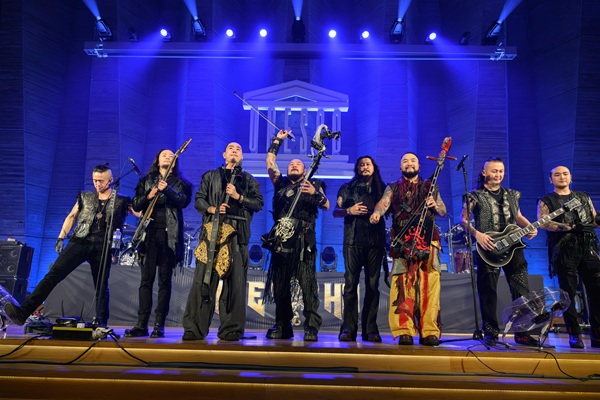 Le groupe The HU en concert sur scène, éclairé en bleu, avec ses instruments traditionnels et électriques