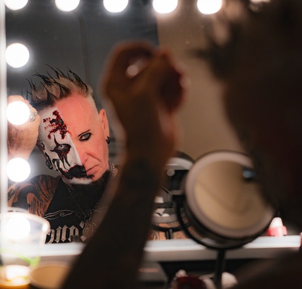 Chad Gray se maquille face à un miroir éclairé par des ampoules