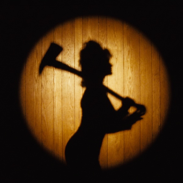 Silhouette d'une personne tenant une hache, projetée sur un mur en bois