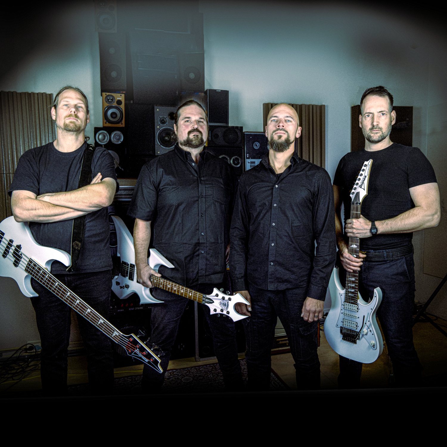 Les quatre membres de The Monolith Deathcult posant en noir devant du matériel de studio, guitares blanches en main