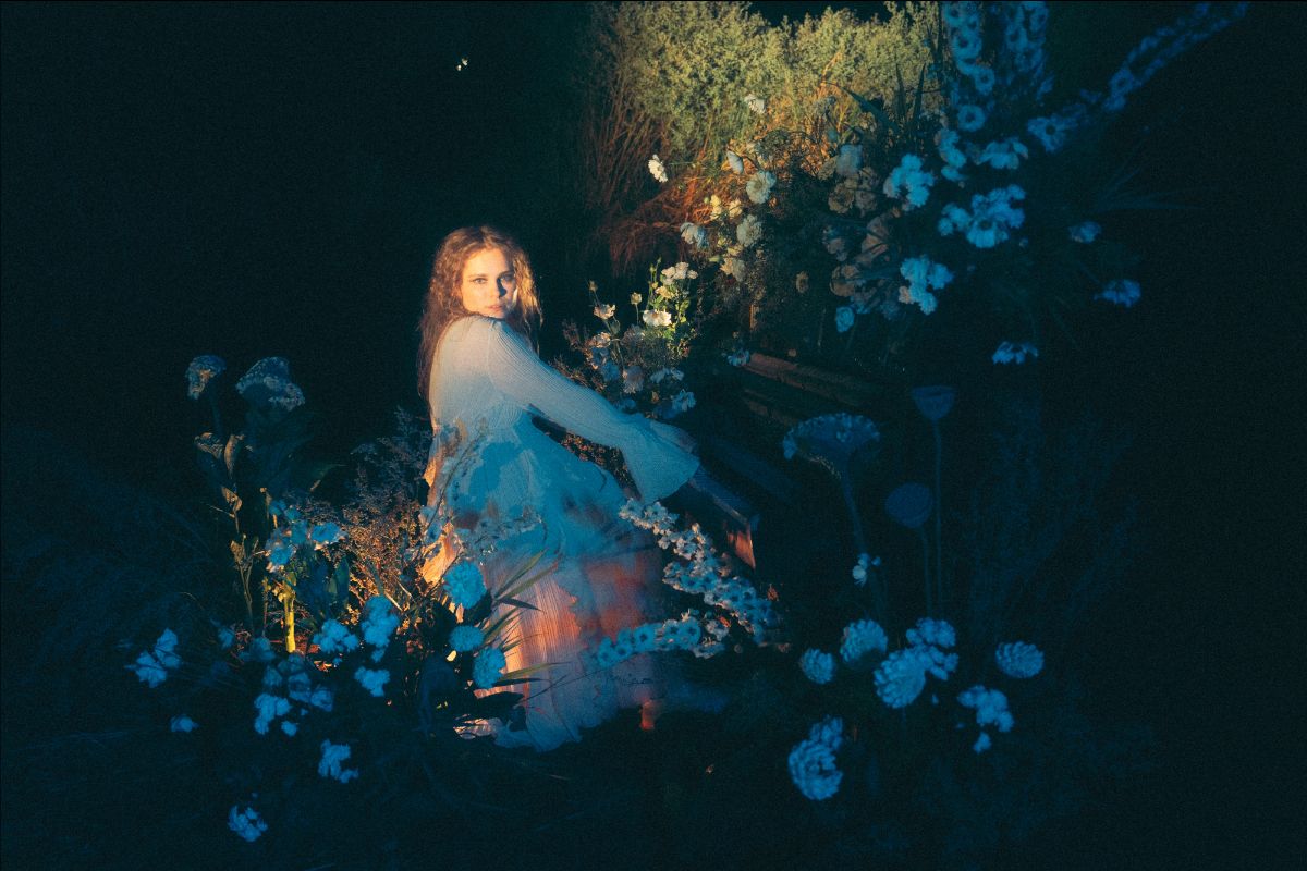 Dikajee photographiée parmi des fleurs bleues dans l'obscurité