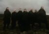 Wardruna dévoile « Helvegen II », une nouvelle version bouleversante Les membres de Wardruna, vêtus de noir, debout dans une lande brumeuse