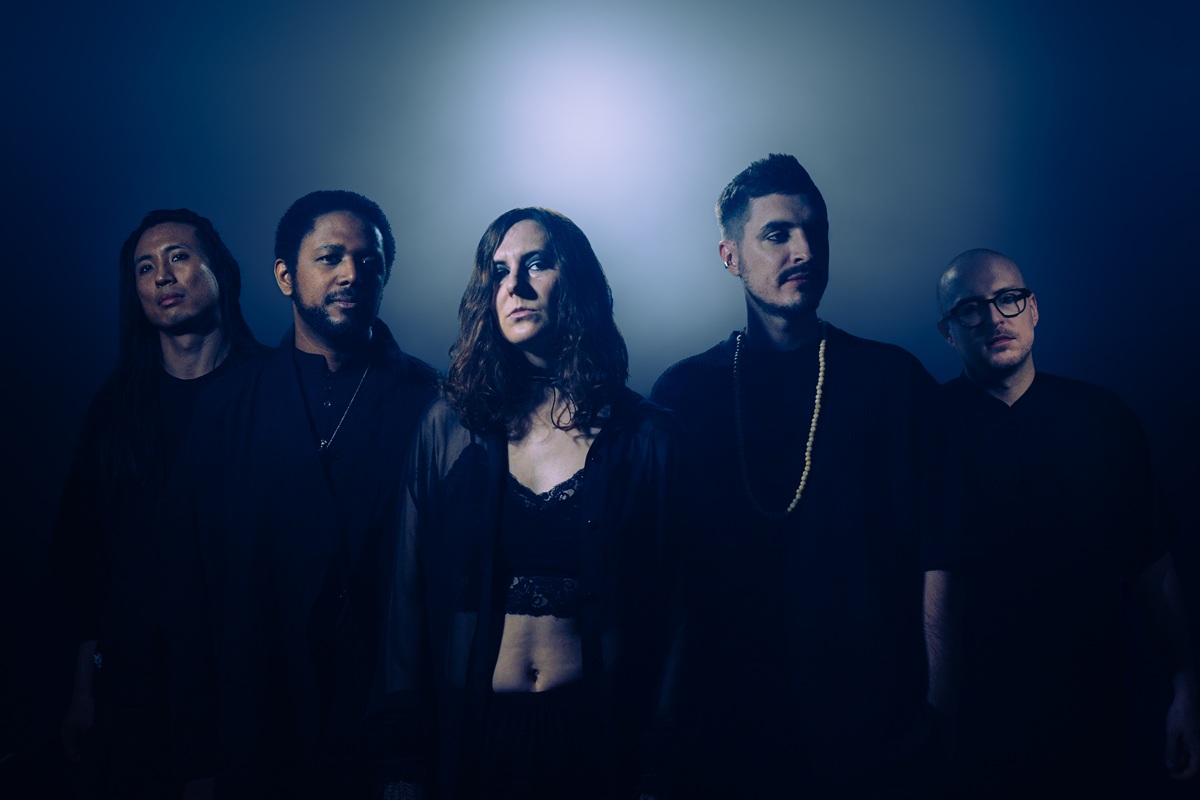 Portrait du groupe DVM SPERO, cinq musiciens en tenue sombre devant un fond bleu