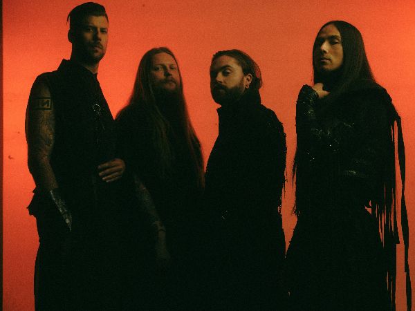 Les membres du groupe Imminence posant devant un fond rouge-orangé