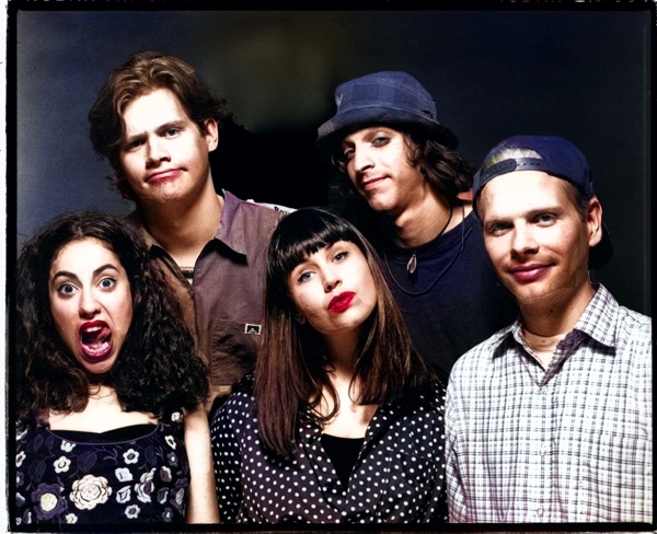 Portrait de groupe de Dance Hall Crashers, cinq membres posant devant un fond sombre