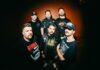 Get The Shot dévoile l’EP « Crucifixion Depiction » Portrait de groupe des six membres de Get The Shot devant un mur orangé