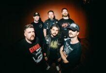 Get The Shot dévoile l’EP « Crucifixion Depiction » Portrait de groupe des six membres de Get The Shot devant un mur orangé