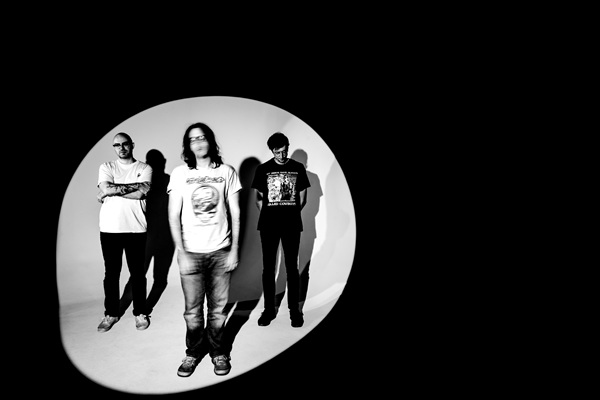 Les trois membres de Cloud Nothings posant en noir et blanc dans un halo de lumière