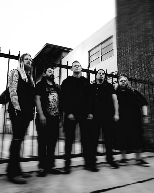 Photo en noir et blanc des cinq membres de Carnifex devant une grille
