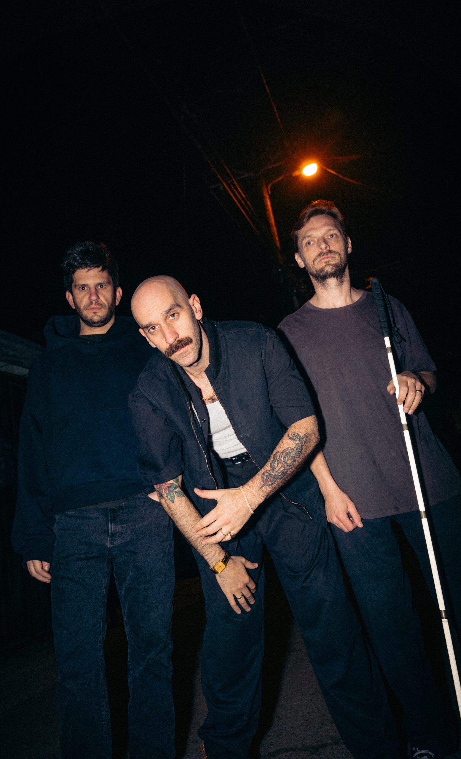 Les trois membres de X Ambassadors de nuit, dans une rue éclairée par un lampadaire