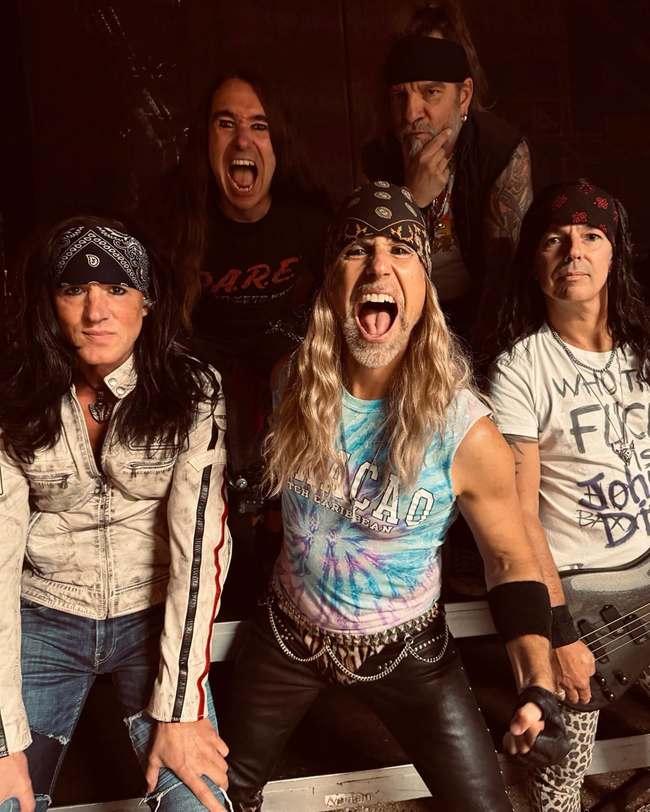 Portrait de groupe de cinq musiciens, dont un chanteur criant face à l'objectif, coiffés de bandanas