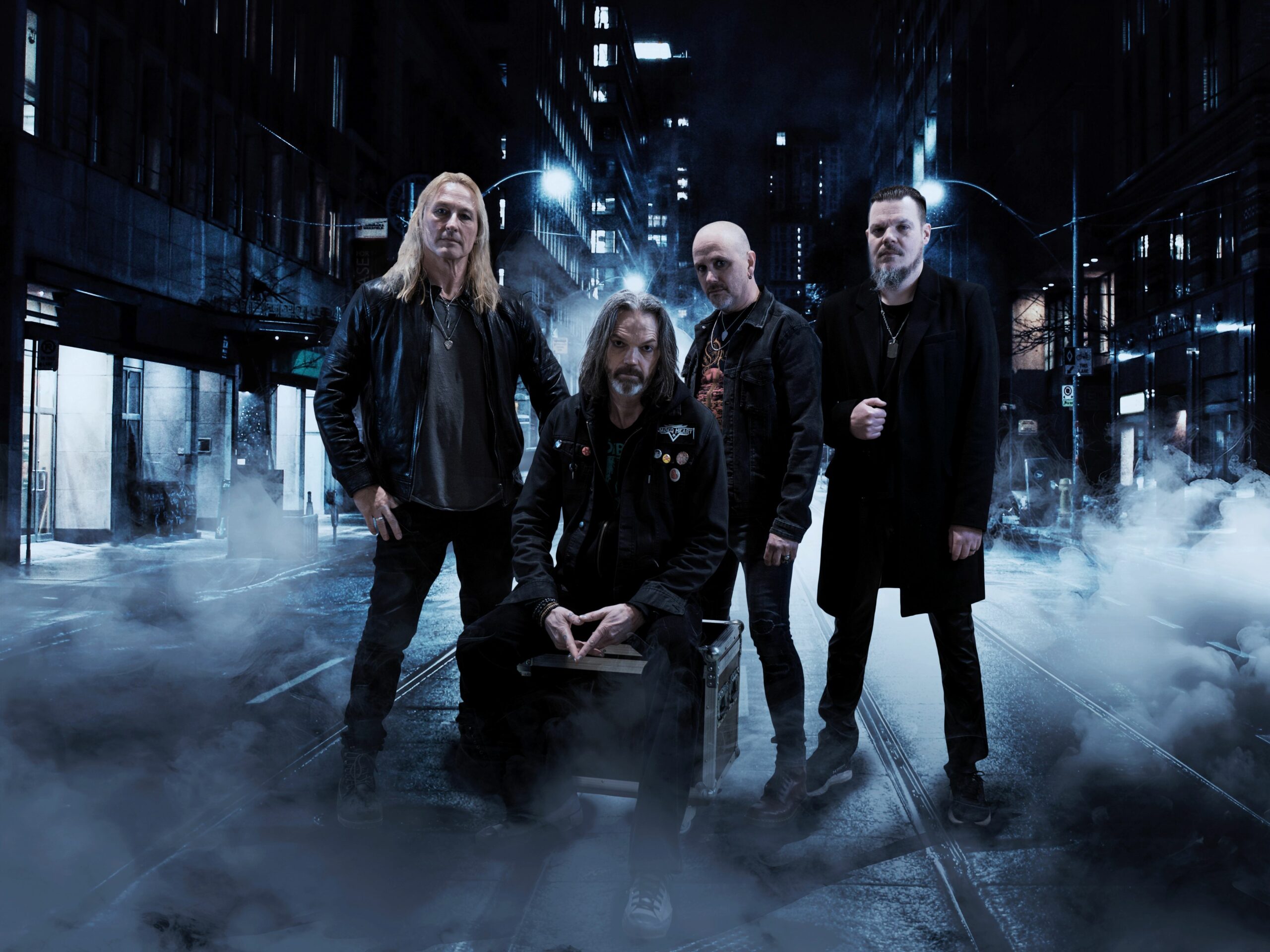 Les quatre membres de Jaded Heart posant dans une rue nocturne embrumée
